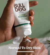 Hand holding a tube of Bulldog Original Moisturiser with a green background