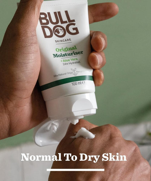 Hand holding a tube of Bulldog Original Moisturiser with a green background